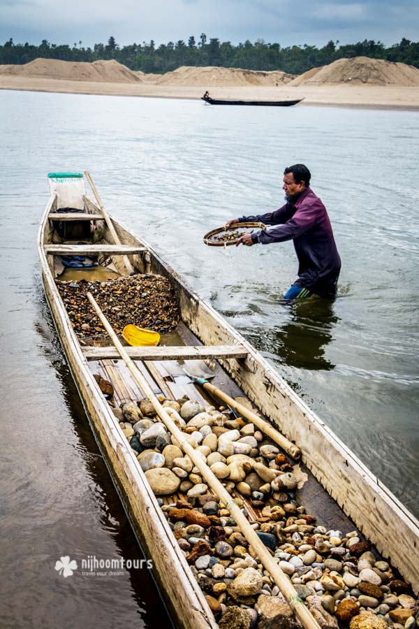 Man collecting stone from river and storing on boat in Jaflong